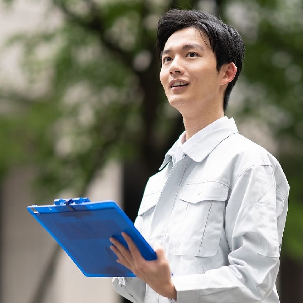作業服を着た男性がファイルを手にしている